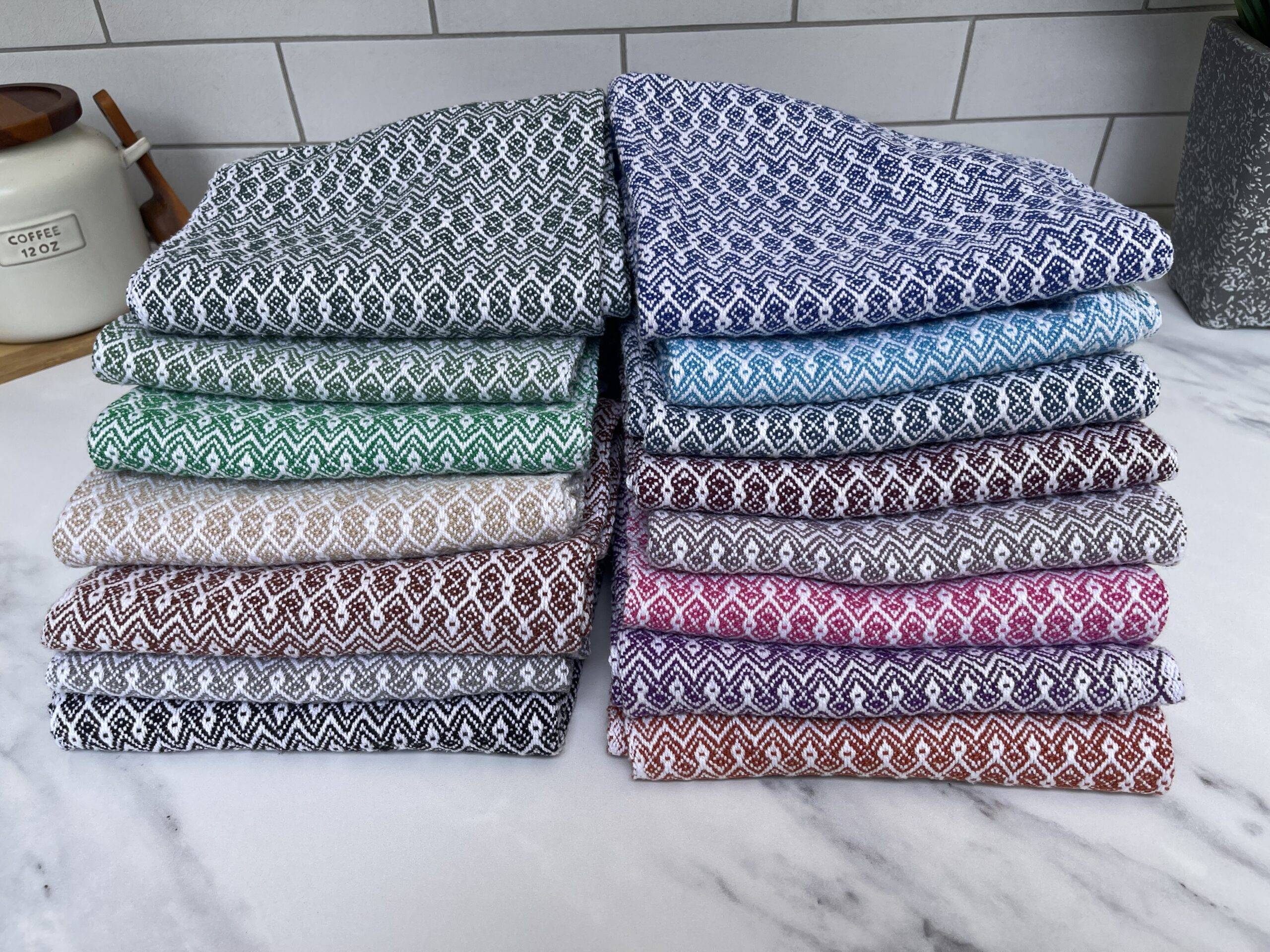 Handwoven folded towels in various colors displayed on top of kitchen countertop