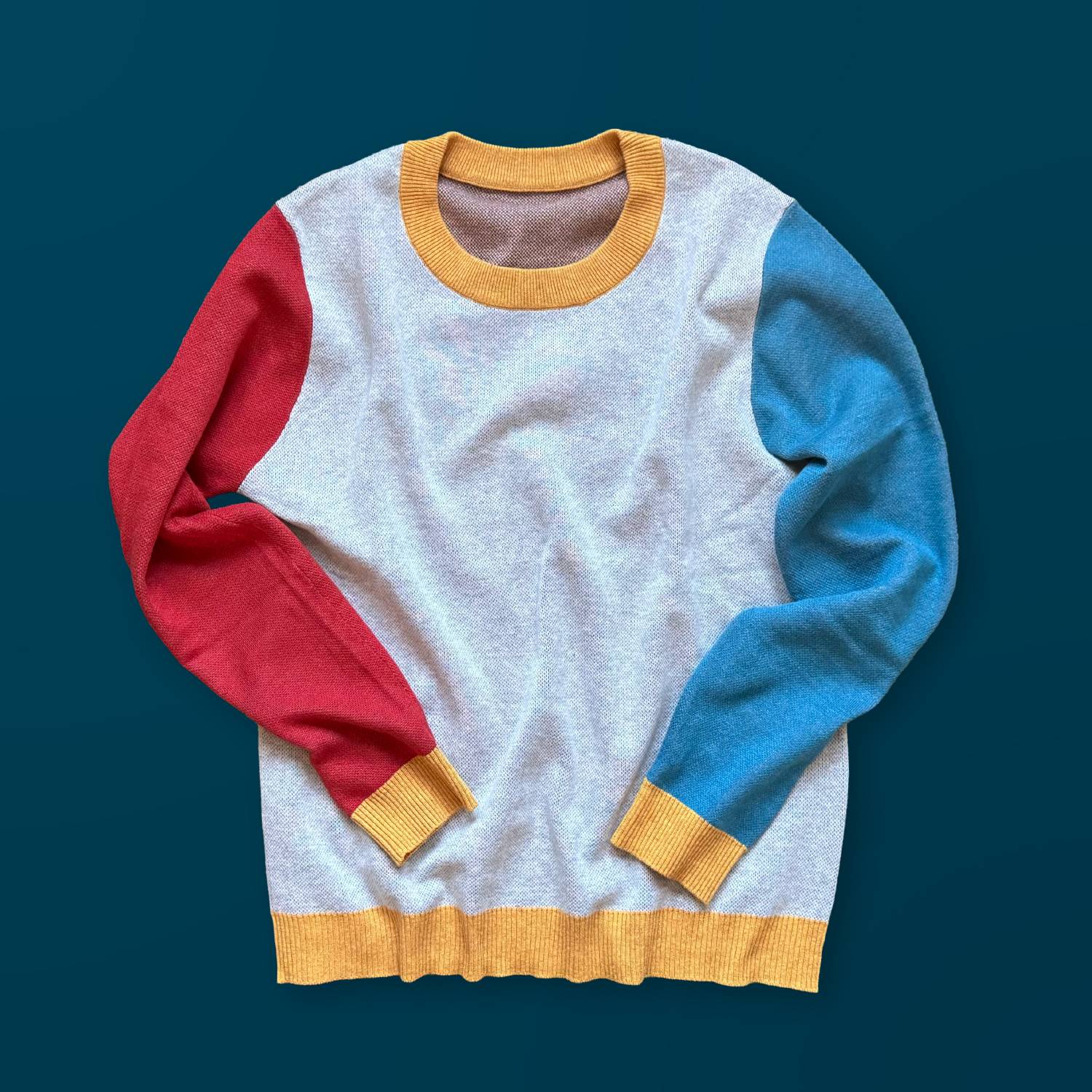 A gray sweater with one orange arm, one blue arm, and yellow trims.