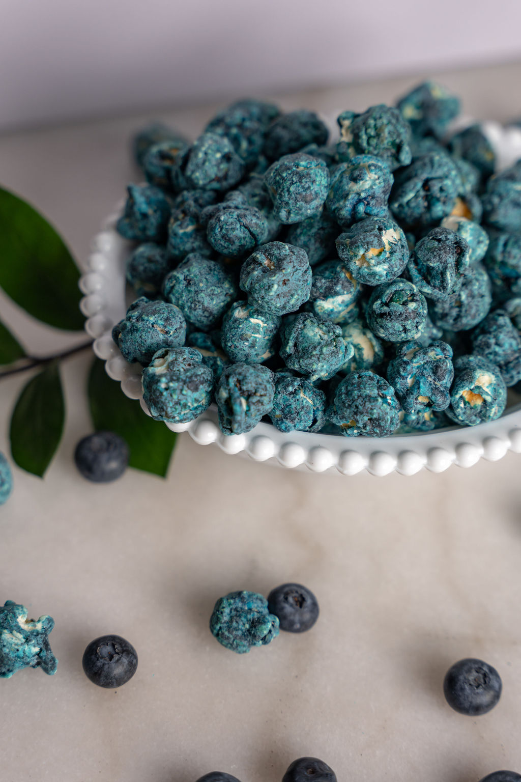 White bowl with blueberry and cream caramel corn spilling out
