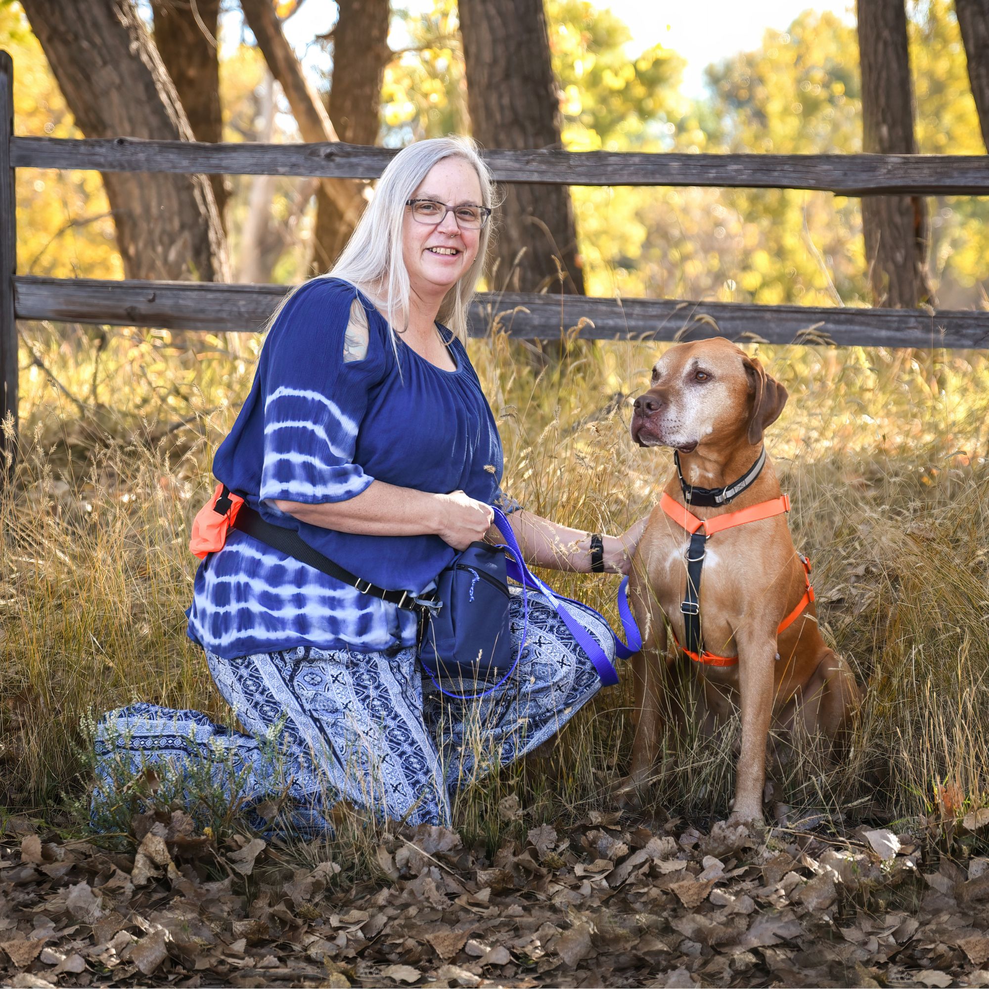 Wendy and Rowan posing in front of a split rail fence on a golden fall day.