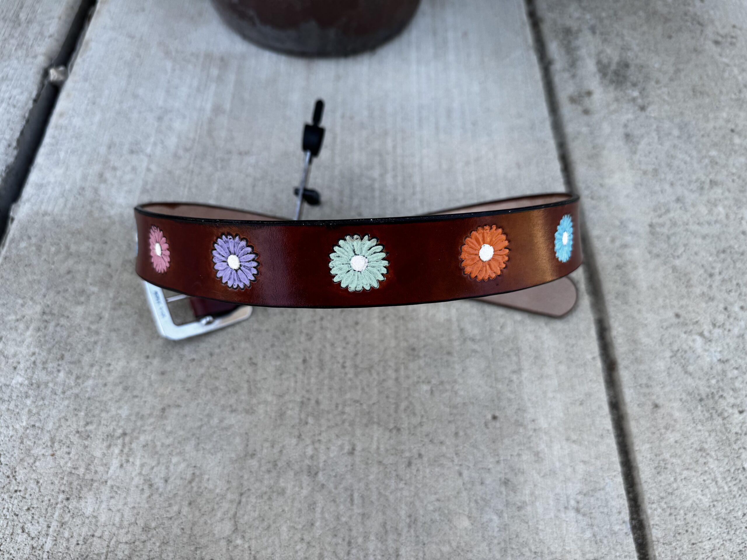 Brown belt with stamped daisy flowers hand painted in various cheery colors with white centers