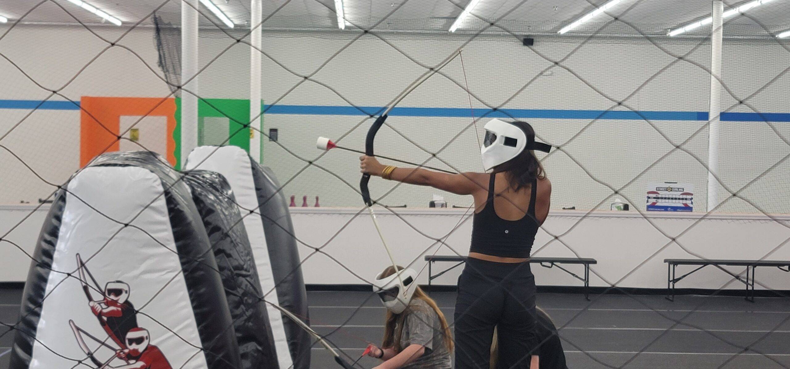Lady shooting an archery tag arrow in an indoor arena