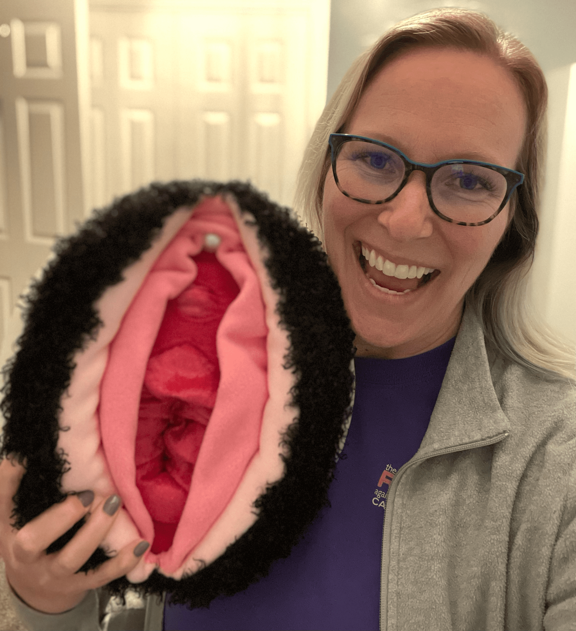 Smiling woman holding a vulva pillow