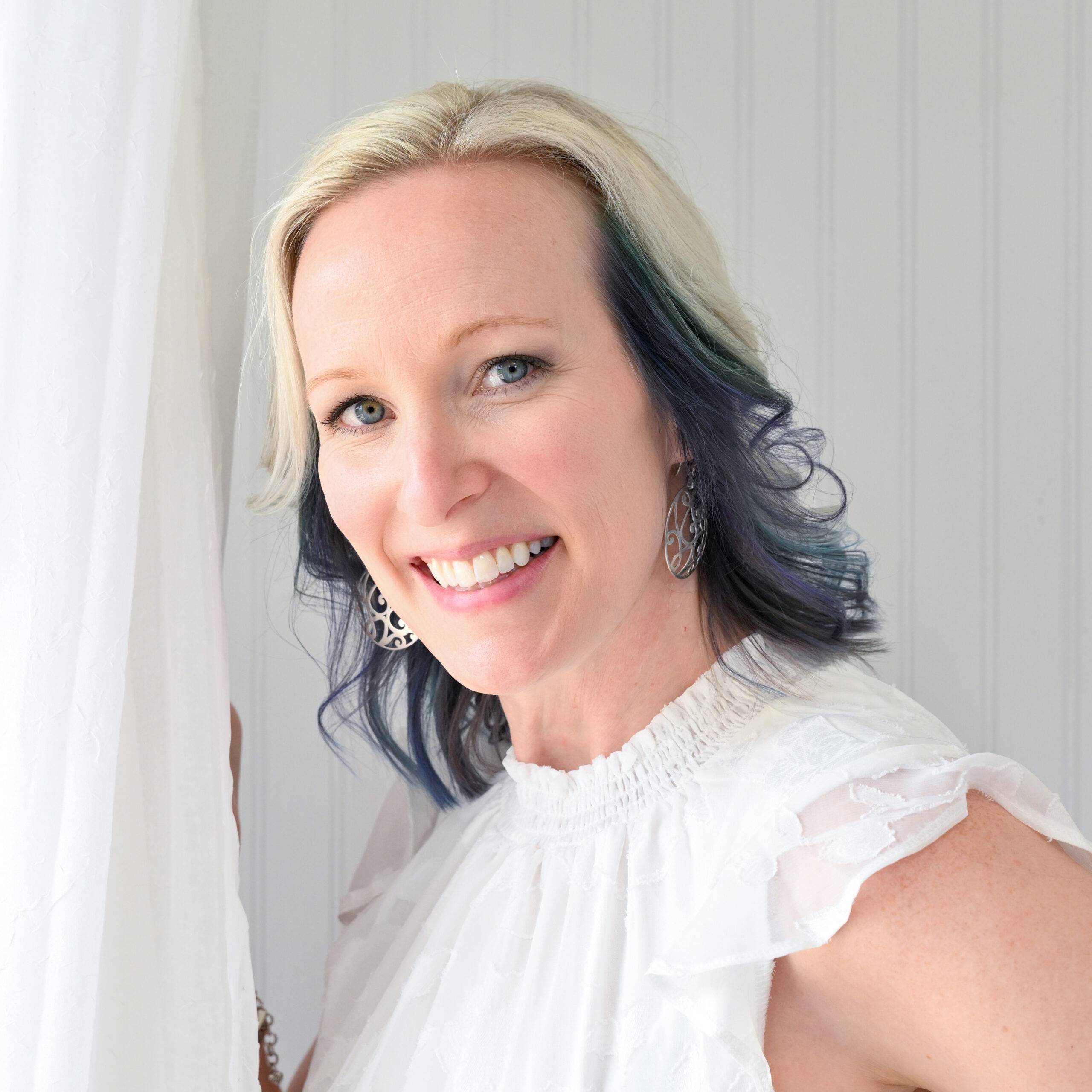 Smiling woman in white dress with blonde and blue hair