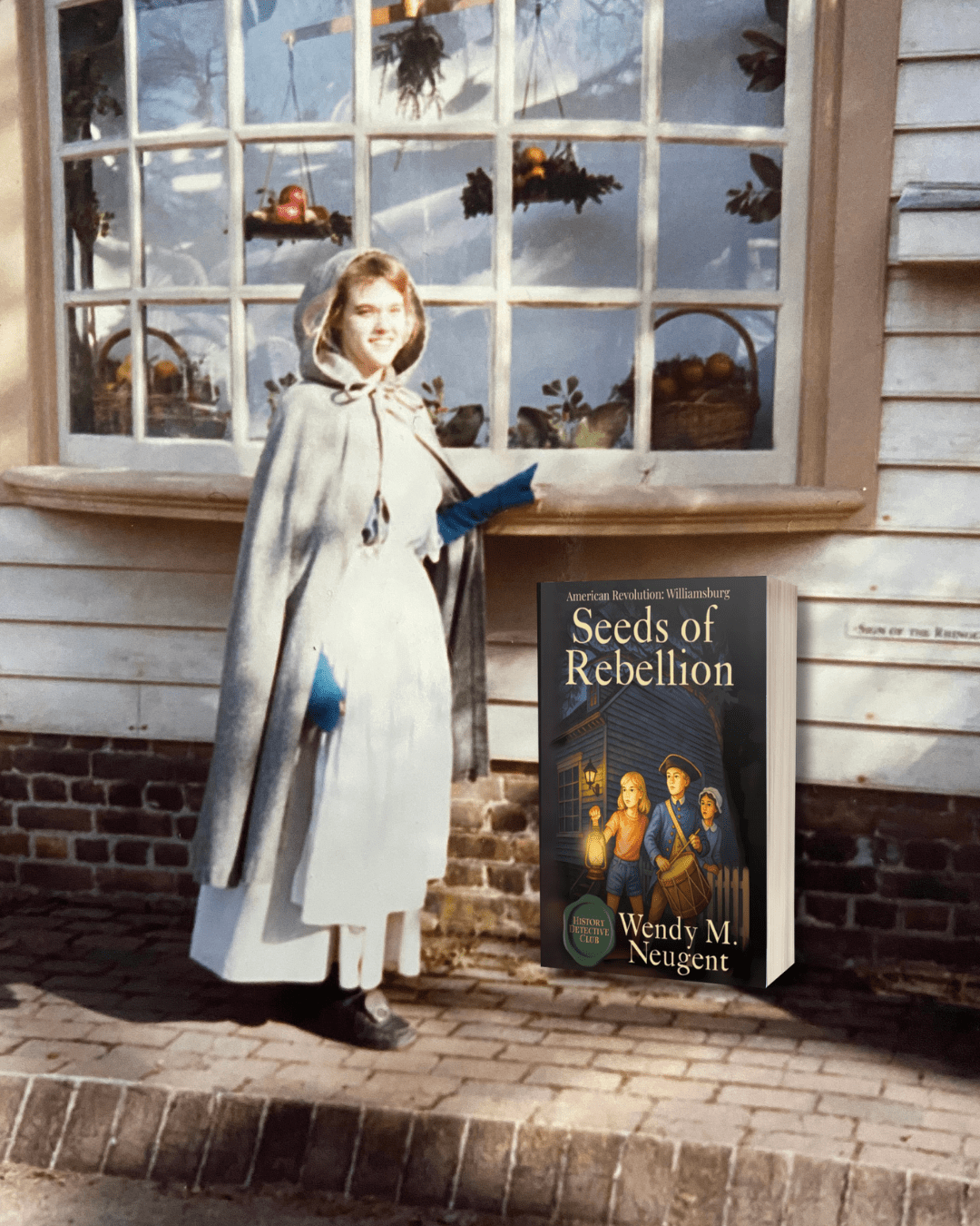 Author Wendy M. Neugent stands in colonial-era clothing in front of the Sign of the Rhinoceros in Williamsburg, with a mockup of her book Seeds of Rebellion visible in the scene.