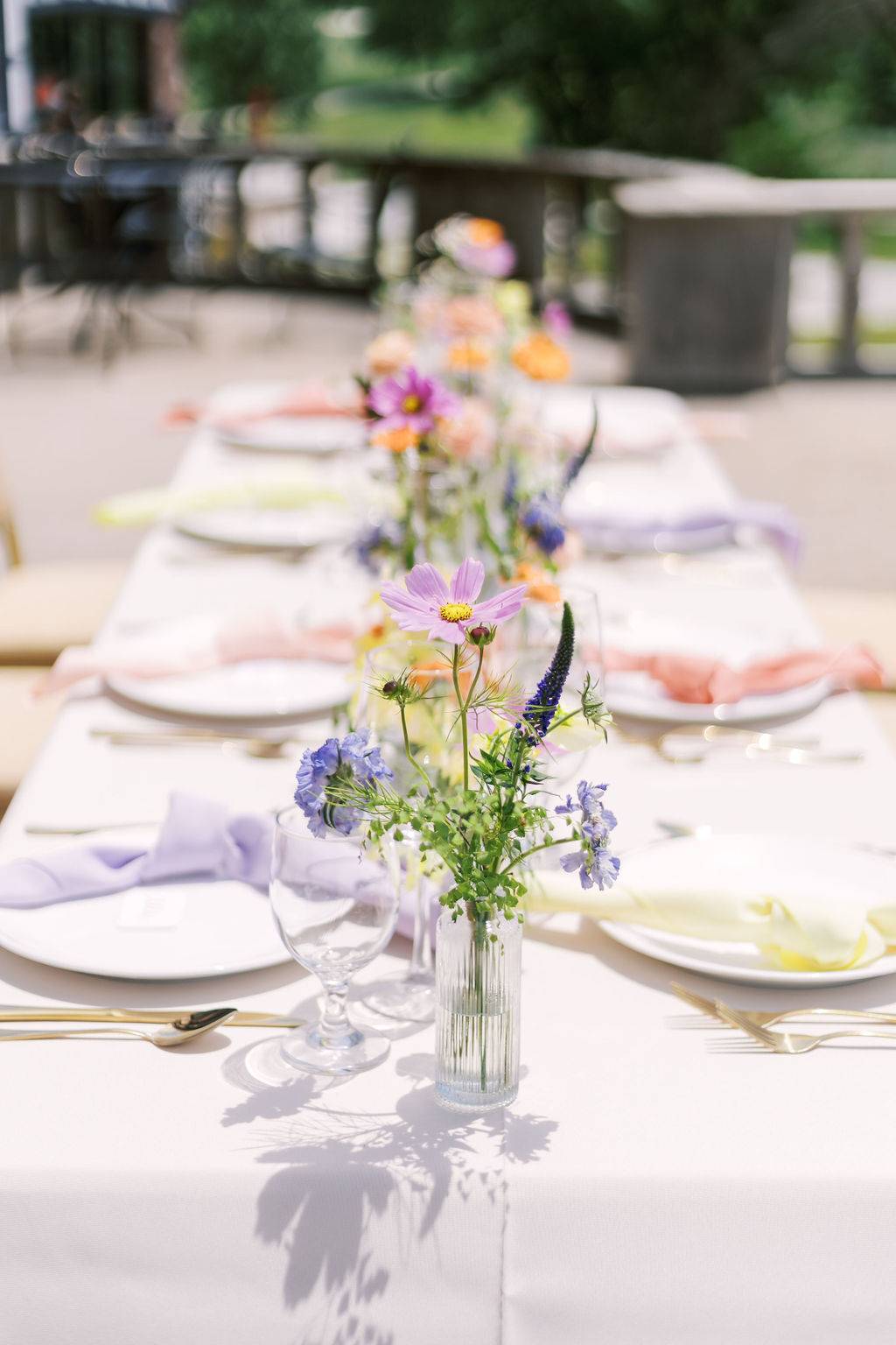 colorful outdoor wedding tablescape with bud vase arrangements